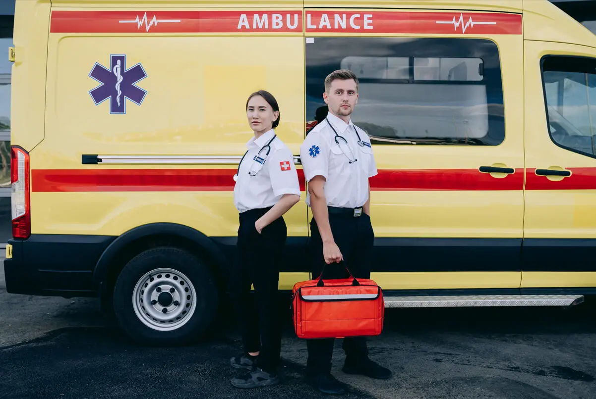 Ambulance on the city street and women and men standing and posing for the camera
